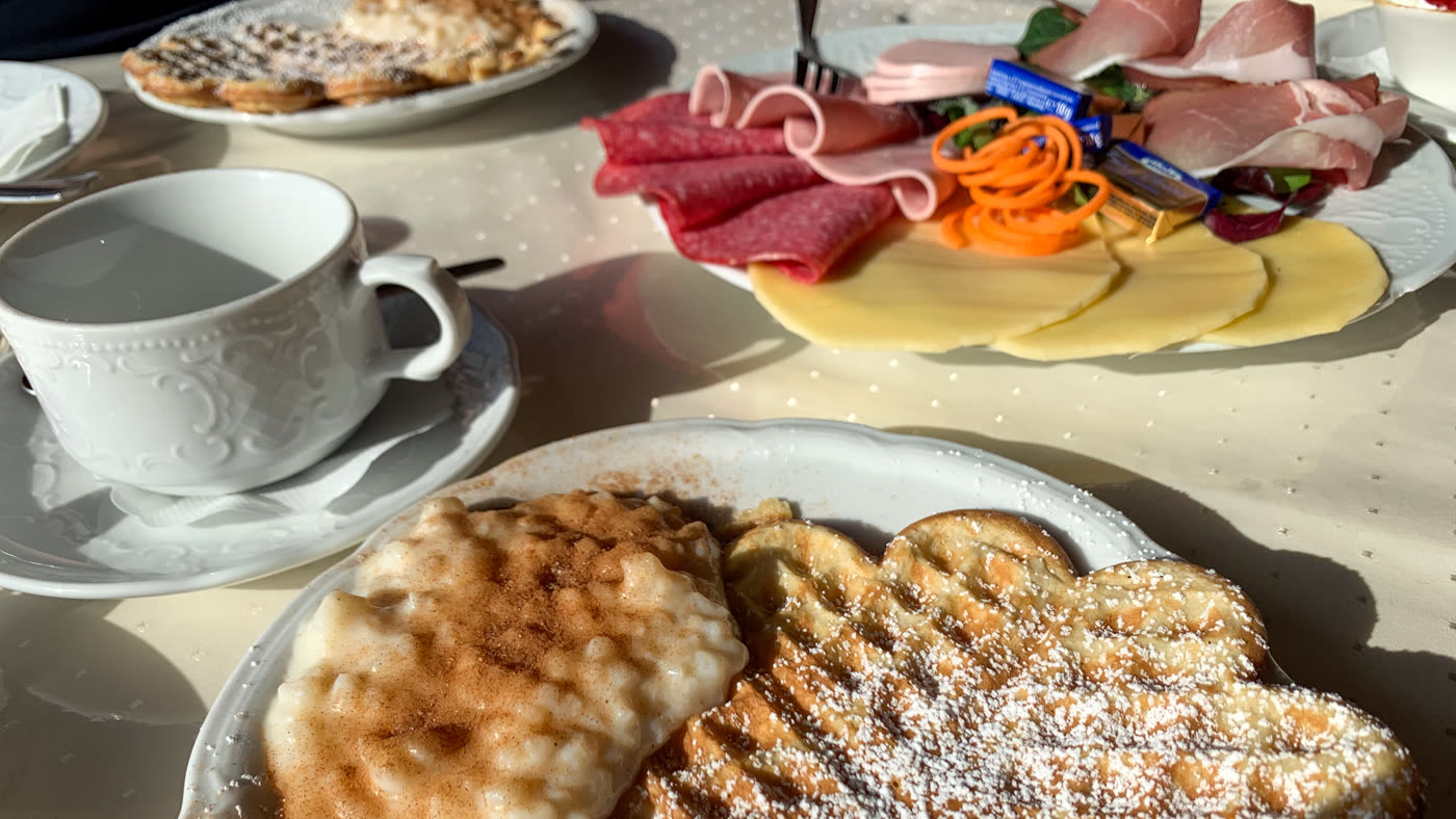 Gedeckter Tisch mit Waffeln, Reisbrei, Aufschnitt und Kaffeetasse Gedeckter Tisch mit Waffeln, Reisbrei, Aufschnitt und Kaffeetasse